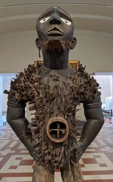 Mangaaka, Nkisi wooden figure, powerful, forward-leaning stance, hands on hips, created to enforce judicial & social order, Bode Mu